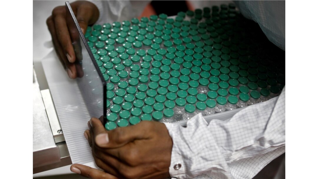 FILE - An employee in personal protective equipment (PPE) removes vials of AstraZeneca's COVISHIELD, coronavirus disease (COVID-19) vaccine from a visual inspection machine inside a lab at Serum Institute of India, in Pune, India, Nov. 30, 2020.