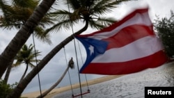 A Puerto Rican flag tied to a swing waves in the wind as Tropical Storm Ernesto approaches Loiza, Puerto Rico, on Aug. 13, 2024.