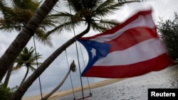 Bendera Puerto Rico tampak diterpa angin kencang saat Badai Tropis Ernesto mendekati Loiza, Puerto Rico, 13 Agustus 2024. 