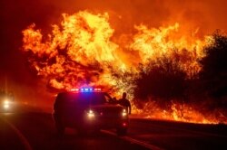 Las llamas se ven por encima de vehículos en la autopista 162 mientras el Bear Fire arde en Oroville, California, el miércoles 9 de septiembre de 2020.