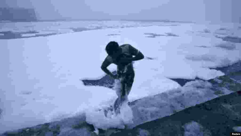 A man cleans foam from his body after taking a bath in the polluted waters of river Yamuna on a cold winter morning in New Delhi January 19, 2012.