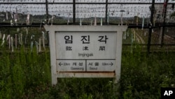 A directional sign showing the distance to North Korea's Kaesong and Seoul stands in front of fences adorned with ribbons bearing messages wishing for the reunification of the two Koreas at the Imjingak Pavilion in Paju, South Korea, May 25, 2024.