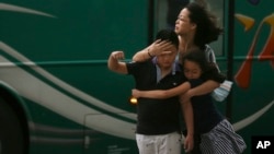 Một người mẹ giữ chặt các con giữa luồng gió của bão Soudelor ở Đài Bắc, Đài Loan, hôm 7/8/2015. 