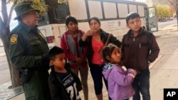 FILE - A migrant family from Central America waits outside the Annunciation House shelter in El Paso, Texas, after a U.S. Immigration and Customs Enforcement officer drops them off, Nov. 29, 2018. 