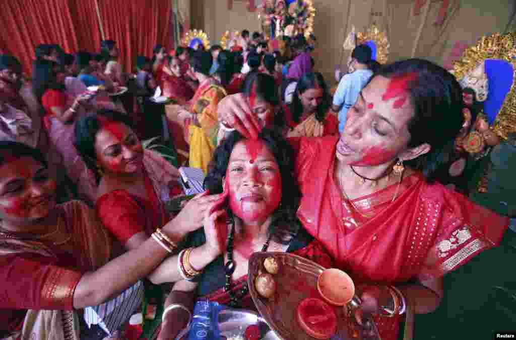 Wanita Hindu mengoleskan 'Sindur' atau bubuk vermillion, pada wajah seorang wanita pada hari terakhir festival memuja Dewi Durga di kota Chandigarh, India utara.