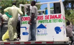A flatbed truck travels on the streets of Port-au-Prince on April 3, 2020. The sign says “Coronavirus is lethal. Wash your hands, protect yourself."