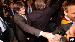 Incoming Catalan President Carles Puigdemont, left, and outgoing Catalan President Artur Mas, center back, wave to the supporters during the investiture session at the Catalonian parliament in Barcelona, Spain, Sunday, Jan. 10, 2016.