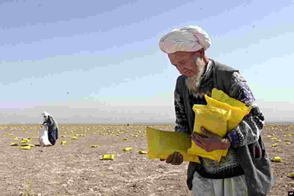 Local Afghan residents pick up food packets of U.S. humanitarian aid dropped by U.S. planes in a field near Khwaja-Bahauddin, anti-Taliban stronghold in northern Afghanistan, October 13, 2001. (AP)