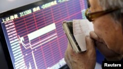 An investor looks at a screen showing stock information, after the new circuit breaker mechanism suspended today's stocks trading, in Shanghai, China, Jan. 7, 2016. 