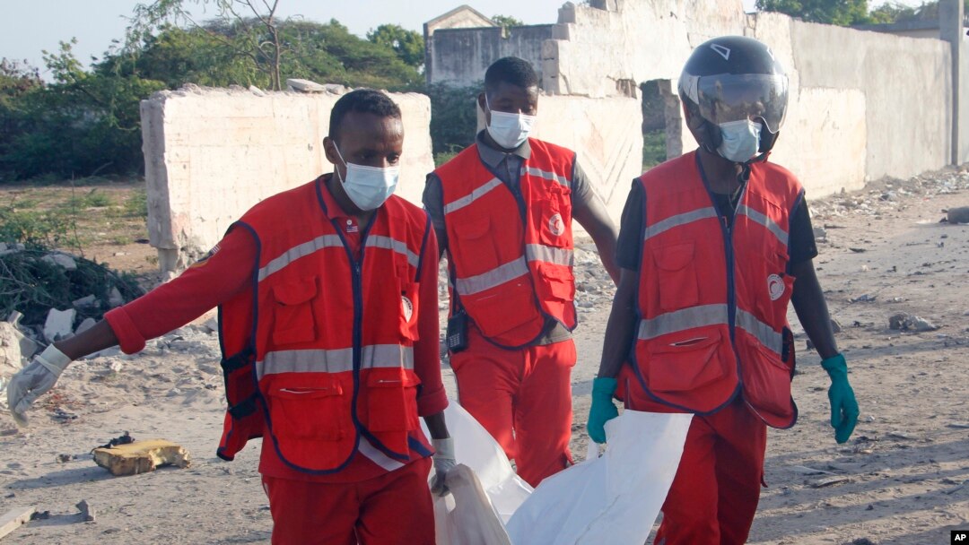 Medical workers carry the body of one of the victims of a suicide car bomb that targeted a convoy in Mogadishu, Somalia, Nov.11, 2021. 