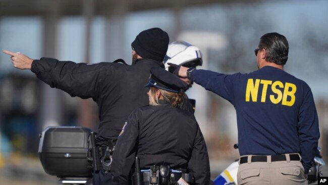 Seorang anggota Dewan Keselamatan Transportasi Nasional Amerika (NTSB) berbincang dengan petugas Kepolisian Philadelphia di lokasi kecelakaan pesawat kecil di Philadelphia, Sabtu, 1 Februari 2025. (Foto: Mat Rourke/AP)