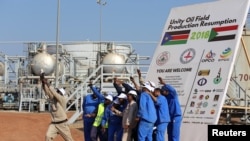 FILE - Workers take a photo during a ceremony marking the restarting of crude oil pumping at the Unity oil fields in South Sudan, Jan. 21, 2019.