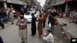 People stand outside their shops after a severe earthquake is felt in Rawalpindi, Pakistan, Jan. 31, 2018.