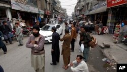 Warga Rawalpindi, Pakistan berdiri di luar toko mereka setelah merasakan gempa bumi yang mengguncang hebat kawasan tersebut, 31 Januari 2018.