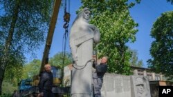 Empleados municipales desmantelan un monumento de la era soviética a los soldados que murieron durante la Segunda Guerra Mundial, en la aldea de Pnikut, en la región de Leópolis, Ucrania, el viernes 12 de mayo de 2023.