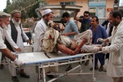 FILE - A wounded man is brought by stretcher into a hospital after an explosion at a mosque in Haskamena district of Jalalabad, east of Kabul, Afghanistan, Oct. 18, 2019.