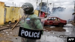 FILE — A Kenyan police officer patrols next to a vandalized car that has been used as a barricade by opposition supporters during anti-government protests in Nairobi, July 19, 2023.