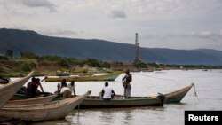 FILE - Fishermen row their boats next to an oil exploration site in Bulisa district, approximately 244 kilometers northwest of Kampala in this undated handout photo from Tullow Oil Uganda, July 2012.
