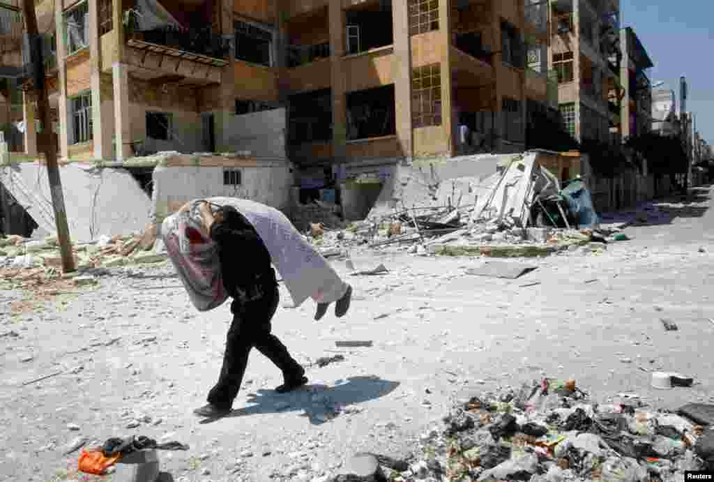 Seorang tentara Pembebasan Suriah membawa jenazah rekan seperjuangannya di Aleppo (16/8).