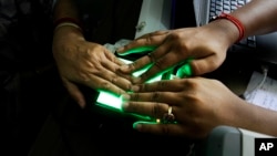 FILE - An operator helps an elderly woman scan her fingerprints as she enrolls for Aadhar, India's unique identification project in Kolkata, India, May 16, 2012. 