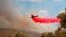 In this photo provided by the Department of Fire and Emergency Services, a firefighting plane dumps retardant on a fire near Wooroloo, northeast of Perth, Australia, Feb. 4, 2021.