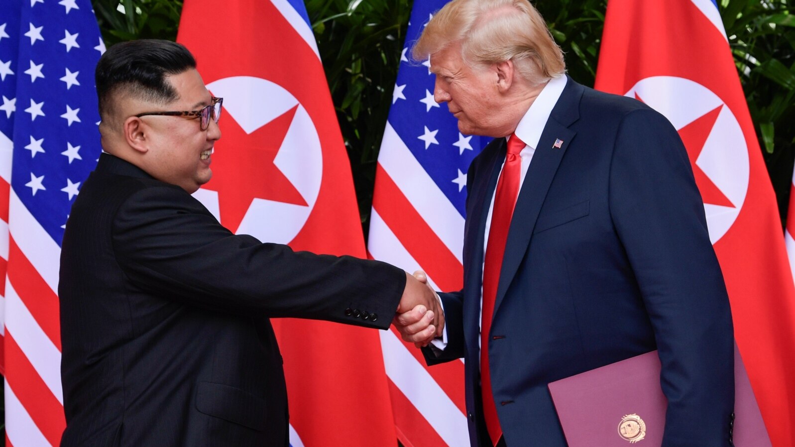 U.S. President Donald Trump and North Korea's leader Kim Jong Un shake hands during the signing of a document after their summit at the Capella Hotel on Sentosa island in Singapore, June 12, 2018. 