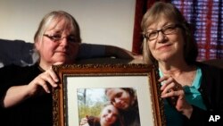 In this June 4, 2014, file photo, mother's Linda Boyle, left and Lyn Coleman hold photo of their married children, Joshua Boyle and Caitlan Coleman, who were kidnapped by the Taliban