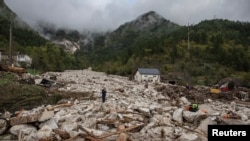 Muškarac stoji među ruševinama nakon klizišta u poplavljenom selu Donja Jablanica