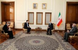 In this photo released by the Iranian Foreign Ministry, South Korean Vice Foreign Minister Choi Jong Kun, center left, speaks with Iranian Foreign Minister Mohammad Javad Zarif, center right, during their meeting in Tehran, Jan. 11, 2021.