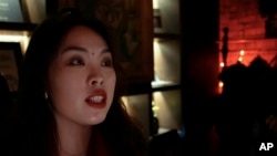 In this image from a video, 28-year-old Sylvia Sun, who works in the music industry, speaks about drinking whisky at a bar in Beijing on Dec. 8, 2023.