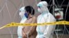 Police officers wearing protective suits pick up an illegal immigrant from an apartment under enhanced lockdown, in Kuala Lumpur, Malaysia, May 1, 2020.