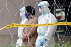 Police officers wearing protective suits pick up an illegal immigrant from an apartment under enhanced lockdown, in Kuala Lumpur, Malaysia, May 1, 2020.