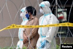 Police officers wearing protective suits pick up an illegal immigrant from an apartment under enhanced lockdown, in Kuala Lumpur, Malaysia, May 1, 2020.