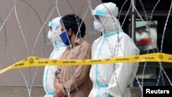 FILE - Police officers wearing protective suits pick up an illegal immigrant from an apartment under enhanced lockdown, in Kuala Lumpur, Malaysia, May 1, 2020.