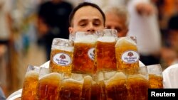 FILE - German Oliver Struempfl competes to set a new world record in carrying one liter beer mugs over a distance of 40 m (131 ft 3 in) in Abensberg, Sept. 7, 2014.