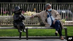 Seorang pria duduk sendirian di sebelah patung beruang Paddington, saat Inggris memberlakukan karantina untuk menahan penyebaran virus corona, 15 April, 2020. 