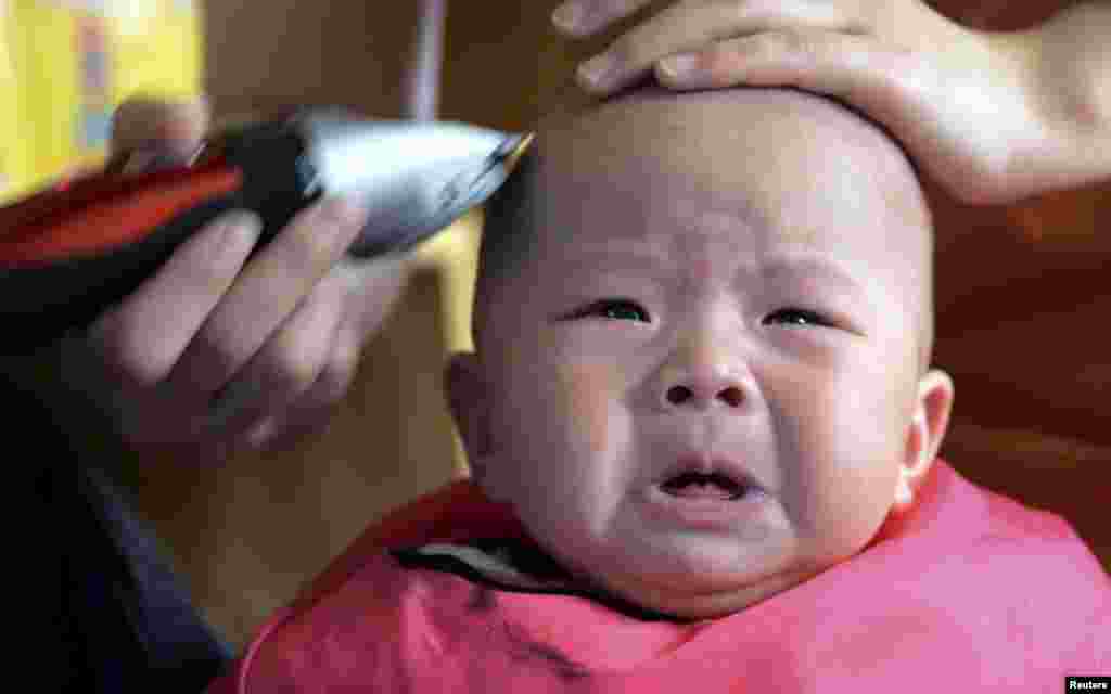 A child cries while getting a haircut at a barbershop during the Longtaitou Festival in Zhengzhou, Henan province March 21, 2015. Longtaitou, which means dragon raising its head, is a traditional Chinese festival held on the second day of the second month of the lunar calendar, which falls on March 21 this year. Many Chinese believe that getting a haircut on this festival is likely to bring good luck.