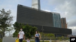 People walk in front of "M+" visual culture museum in the West Kowloon Cultural District of Hong Kong, Monday, March 29, 2021. (AP Photo/Kin Cheung)