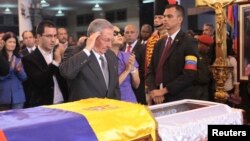 El presidente cubano Raúl Castro saluda frente a los restos de Chávez en Caracas. Los médicos cubanos que le atendieron serán condecorados.