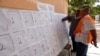 An official assists a voter to find his name before voting inside a school in Tripoli, June 25, 2014.