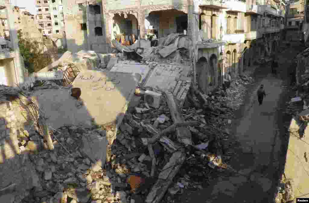 A man walks past damaged buildings in the besieged area of Homs, Syria, Jan. 29, 2014.