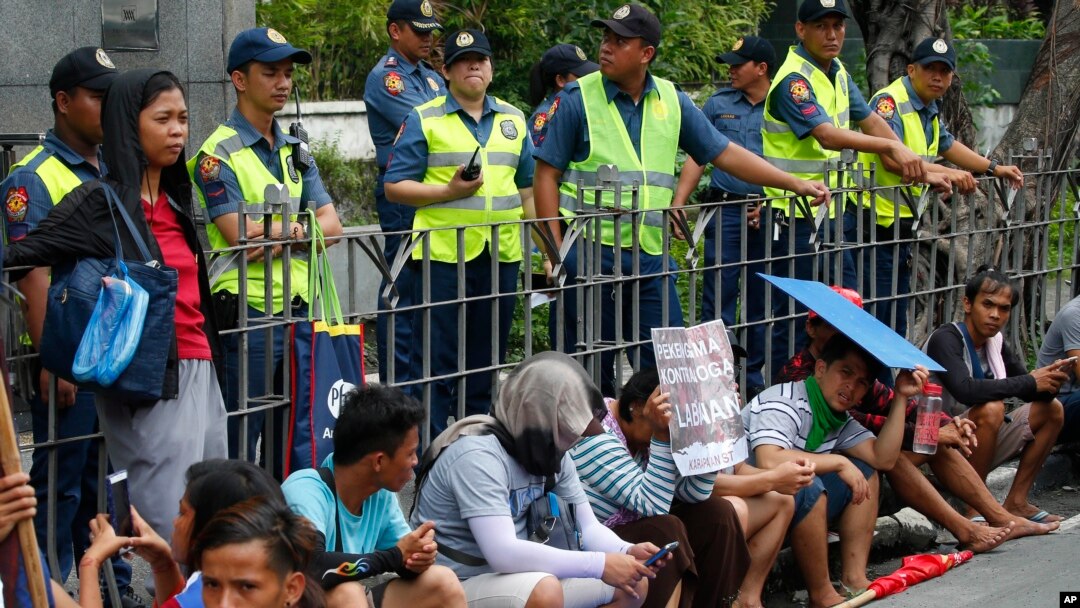 Polisi mengawasi para pengunjuk rasa di depan gedung Konsulat China, dalam aksi protes militerisasi Cina atas kawasan di Laut Cina Selatan yang disengketakan, di distrik keuangan kota Makati di timur Manila, Filipina, Sabtu, 21 Juli 2018. 