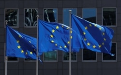 FILE - European Union flags flutter outside the European Commission headquarters in Brussels, Belgium, June 25, 2020.