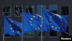 FILE - European Union flags flutter outside the European Commission headquarters in Brussels, Belgium, June 25, 2020. 