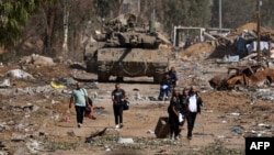 Palestinci koji bježe sa sjevera putem Salaheddine u okrugu Zeitoun na južnoj periferiji grada Gaze, prolaze pored tenkova izraelske vojske 24. novembra 2023.