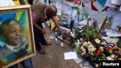 A wellwisher places a picture outside the hospital where ailing former South African President Nelson Mandela is being treated in Pretoria, July 11, 2013.