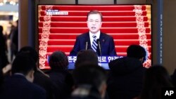 People watch a TV screen showing the live broadcast of South Korean President Moon Jae-in's New Year's speech at the Seoul Railway Station in Seoul, Jan. 7, 2020. 