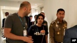 El jefe de la Policía de Inmigración, mayor general Surachate Hakparn, camina con la joven saudí Rahaf Mohammed Alqunun antes de salir del aeropuerto de Suvarnabhumi en Bangkok, Tailandia, el 7 de enero de 2019.