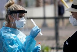 Nurse practitioner Debbi Hinderliter, left, collects a sample from a woman at a coronavirus testing site near the nation's busiest pedestrian border crossing, in San Diego, Aug. 13, 2020.