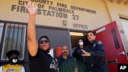 Manifestantes hablan con miembros del Departamento de Bomberos del condado de Los Ángeles cerca del sitio donde Robert Fuller fue encontrado colgando de un árbol, el lunes 15 de junio de 2020 en Palmdale, California.
